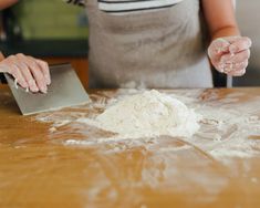 a woman is kneading dough on a wooden table