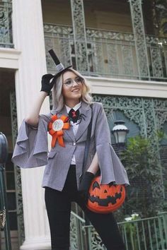 a woman dressed up as a witch holding a pumpkin