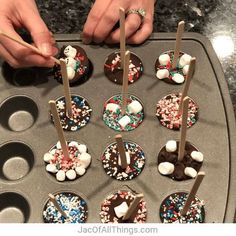 someone decorating cupcakes with chocolate and sprinkles on a tray