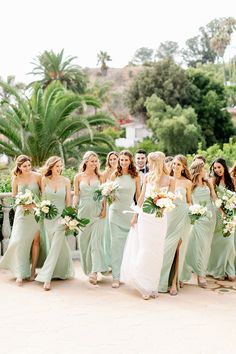 a group of bridesmaids in mint green dresses and bouquets pose for a photo