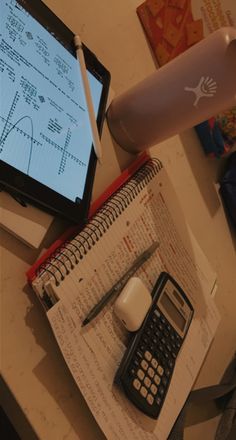 an open notebook with a calculator, pen and cell phone on top of it