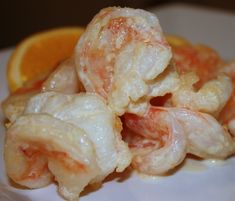 shrimp and oranges are piled on top of each other in a white plate with sauce