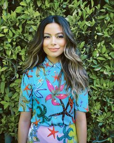 a woman standing in front of a bush wearing a blue shirt with starfishs on it