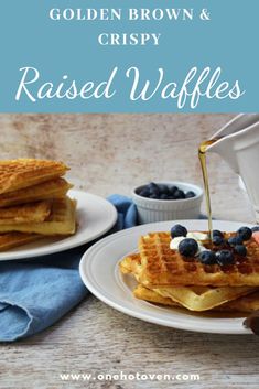 some waffles with blueberries and syrup being poured onto them on white plates