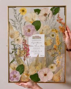 a person holding up a floral frame with flowers on it