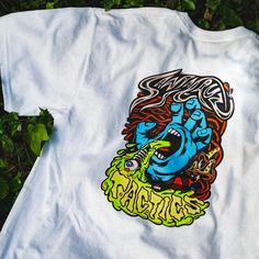 a t - shirt with an image of a blue demon on it sitting in the grass