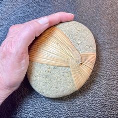 a person's hand holding a rock with a bamboo fan on it