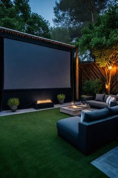 an outdoor movie theater with couches and firepit in the background at night time