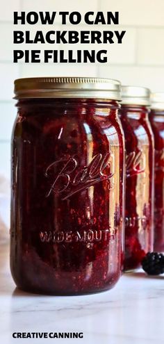 three jars filled with blackberry pie filling sitting on top of a counter next to blackberries