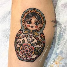 a woman's leg with a tattoo on it that has an image of a doll and flowers