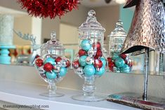 two glass vases filled with ornaments on top of a mantle