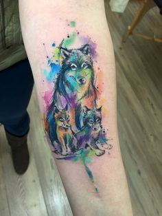 a watercolor wolf tattoo on the left inner arm and leg, with three cubs