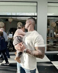 a man holding a baby in his arms while standing next to a store front window