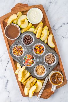 an assortment of fruit and nuts in muffin tins with dipping sauce on the side