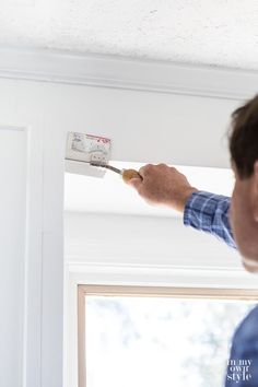 a man is painting the ceiling with white paint