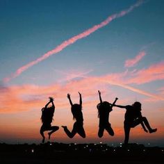 three girls jumping in the air at sunset