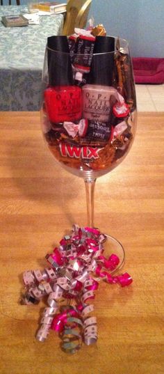 a wine glass filled with lots of different types of nail polishes and confetti