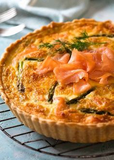 a quiche with salmon and asparagus on top sits on a cooling rack