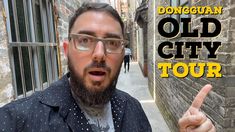 a man with glasses is pointing to the camera in front of an old city tour sign