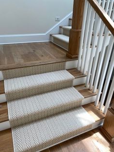 the stairs are made of wood and have white handrails with herringbone carpet