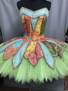 a dress made out of tulle with colorful designs on the front and bottom, sitting on a mannequin