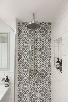 a bathroom with a shower head, mirror and sink in the corner next to tiled walls