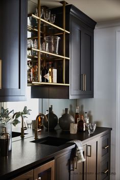 a kitchen counter topped with lots of bottles and glasses next to a cabinet filled with liquor