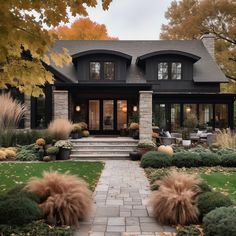 a large house with lots of windows and plants in the front yard, along with steps leading up to it