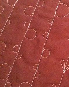 a close up of a quilted surface with circles and lines drawn on the fabric