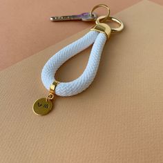 a white rope keychain with a gold charm