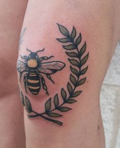 a woman's thigh with a tattoo of a bee on it, and an olive branch