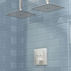 two square shower heads mounted on the side of a blue tiled wall