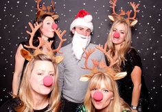 three women and one man are posing for a photo with reindeer noses