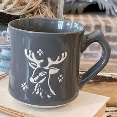 a blue mug with a white deer design on it sitting on a table next to other items