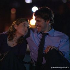 a man and woman sitting next to each other in front of a lit up candle