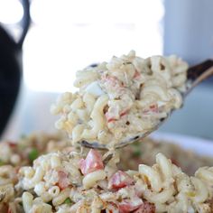 a spoon full of macaroni salad being lifted from a bowl