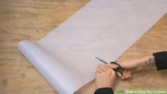 a person cutting paper on top of a wooden table