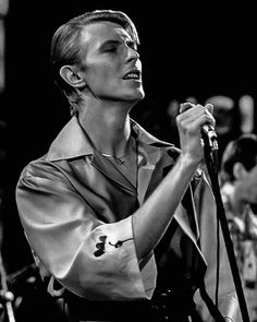 a man standing in front of a microphone with his hands on the mic and looking up