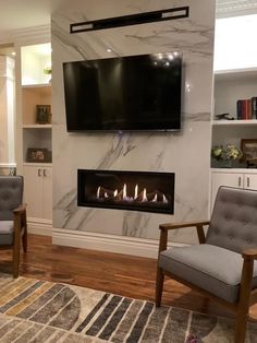 a living room with two chairs and a flat screen tv mounted on the wall above it