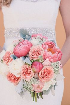 a bride holding a bouquet of pink and white flowers