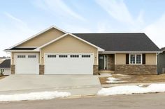 a house with two garages and snow on the ground