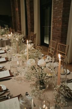 a long table with white flowers and candles on it is set for a formal dinner