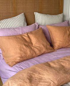 an unmade bed with two pillows on top of it and purple sheets in the middle