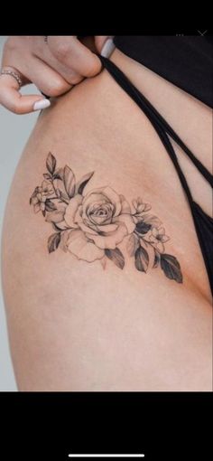 a woman's stomach with a rose tattoo on her side and the bottom part of her belly