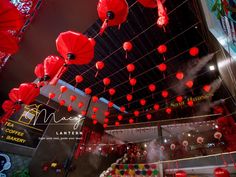 many red lanterns hanging from the ceiling in a building with lights and decorations on it