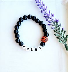 a beaded bracelet with the word koby on it next to a purple flower