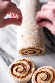 two cinnamon rolls are being made on a marble counter top with one rolled up and the other unwrapped