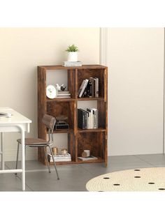 a room with a desk, chair and bookshelf in front of a white wall