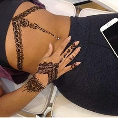 a woman with tattoos on her stomach and arm is sitting in front of a cell phone