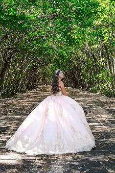 a woman in a wedding dress walking through the woods